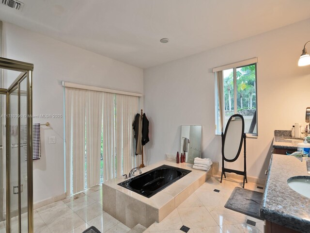 full bath with vanity, a garden tub, and baseboards