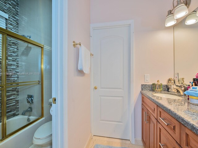 bathroom with shower / bath combination with glass door, double vanity, toilet, baseboards, and tile patterned flooring