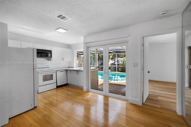 2020 NW 33rd Ct, Oakland Park, FL 33309 - kitchen with white appliances, french doors, light wood finished floors, light countertops, and visible vents
