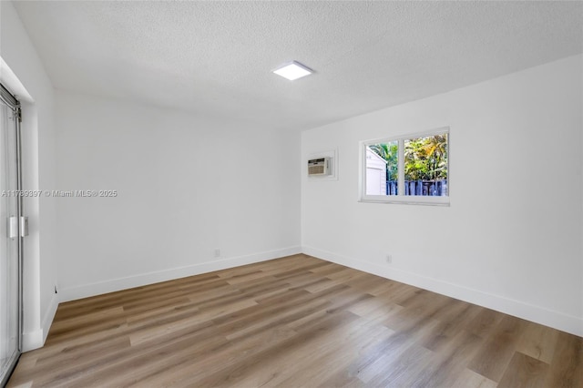 2020 NW 33rd Ct, Oakland Park, FL 33309 - unfurnished room featuring a wall mounted air conditioner, baseboards, wood finished floors, and a textured ceiling