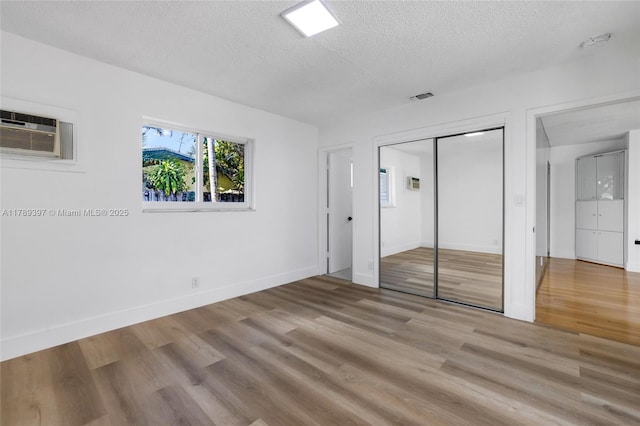 2020 NW 33rd Ct, Oakland Park, FL 33309 - unfurnished bedroom featuring a wall mounted air conditioner, wood finished floors, a textured ceiling, a closet, and baseboards