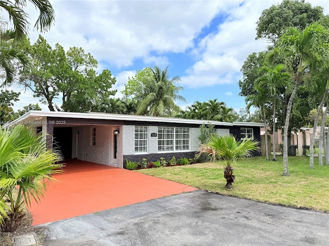 ranch-style house with stone siding, a front lawn, aphalt driveway, and an attached carport