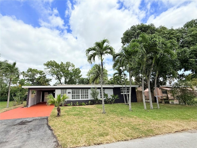 ranch-style house featuring a front lawn, aphalt driveway, and an attached carport