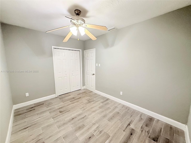 unfurnished bedroom with light wood finished floors, baseboards, visible vents, and a closet
