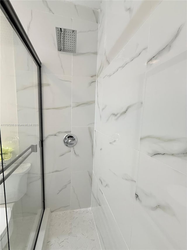full bath featuring toilet and a marble finish shower