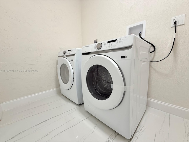 laundry area featuring baseboards, marble finish floor, a textured wall, washer and dryer, and laundry area