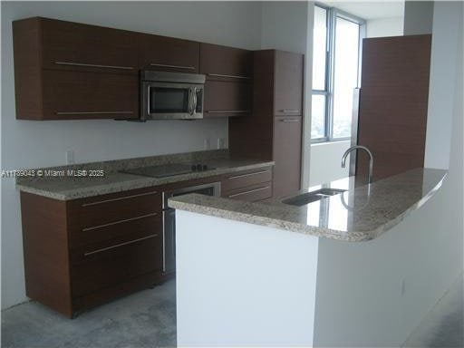 2681 N Flamingo Rd Unit 1501S, Sunrise, FL 33323 - kitchen with dark brown cabinetry, a sink, black electric cooktop, a peninsula, and stainless steel microwave