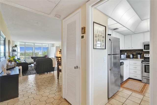 2671 S Course Dr Unit 409, Pompano Beach, FL 33069 - kitchen with tasteful backsplash, open floor plan, white cabinetry, light countertops, and appliances with stainless steel finishes