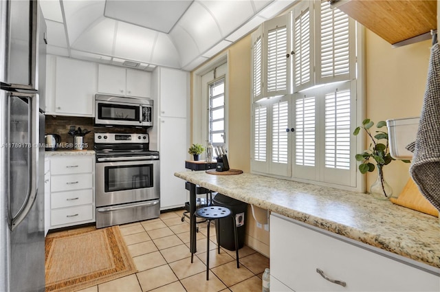 2671 S Course Dr Unit 409, Pompano Beach, FL 33069 - kitchen with stainless steel appliances, backsplash, white cabinetry, light countertops, and light tile patterned floors