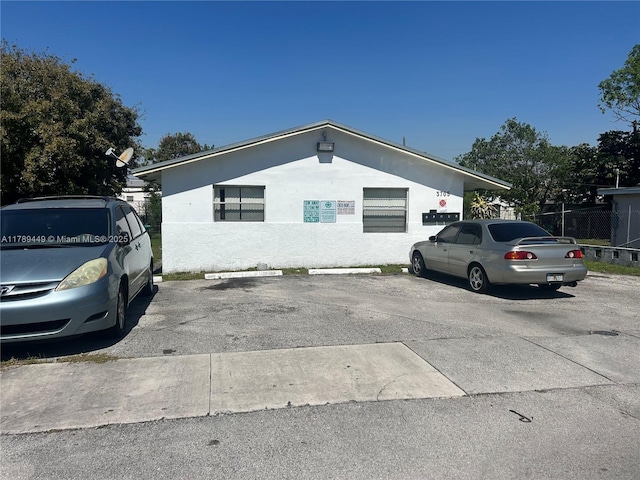 view of property exterior with uncovered parking and stucco siding