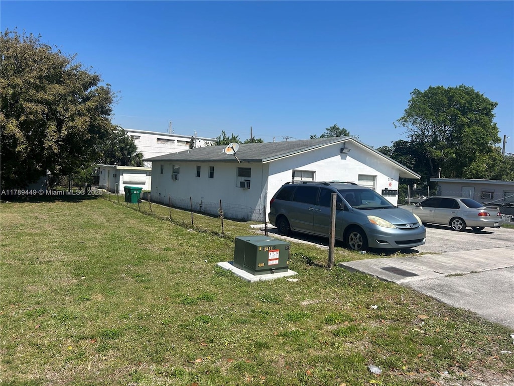 view of home's exterior with a lawn and fence