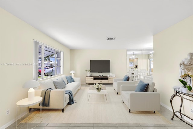 living room with a chandelier, visible vents, tile patterned floors, and baseboards