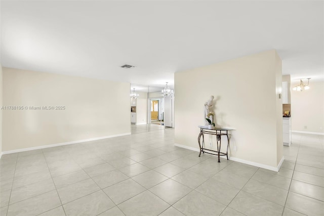 unfurnished room with baseboards, a notable chandelier, and light tile patterned flooring