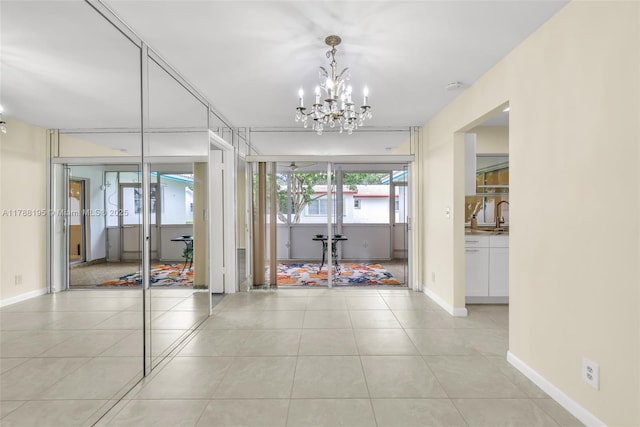 interior space featuring baseboards, a sink, a notable chandelier, and light tile patterned floors