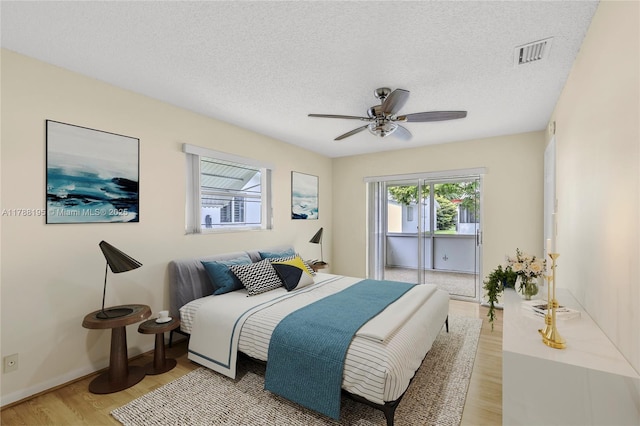bedroom featuring visible vents, a ceiling fan, baseboards, light wood-style flooring, and a textured ceiling