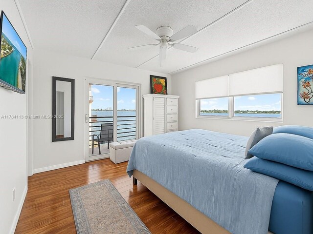 4500 N Flagler Dr Unit C24, West Palm Beach, FL 33407 - bedroom with multiple windows, access to exterior, a textured ceiling, baseboards, and wood finished floors