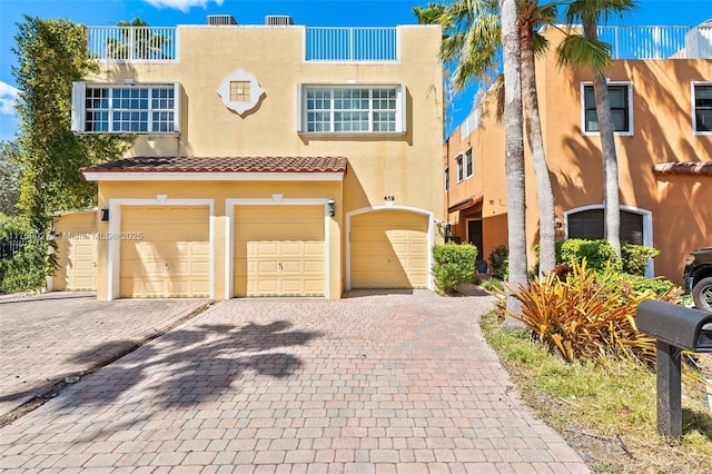 view of front of home featuring a tile roof, an attached garage, stucco siding, and decorative driveway