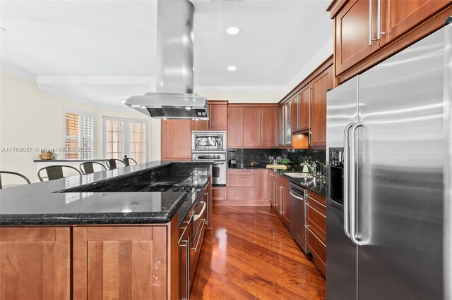 419 SW 5th St Unit 419, Fort Lauderdale, FL 33315 - kitchen with stainless steel appliances, ornamental molding, island range hood, a kitchen island, and dark stone countertops