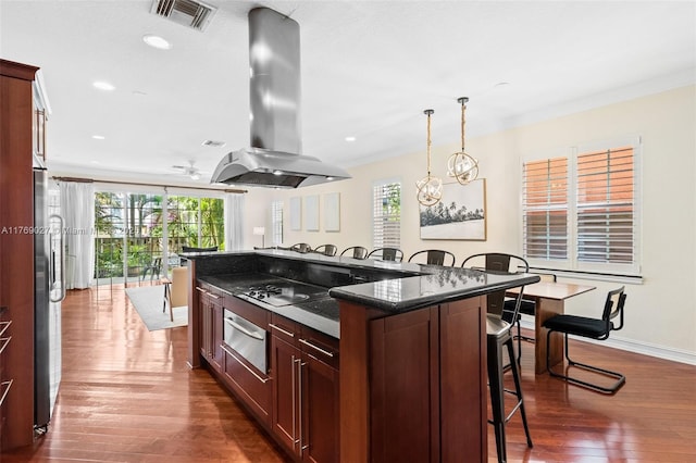 kitchen featuring dark wood-style flooring, island range hood, a wealth of natural light, and a breakfast bar area