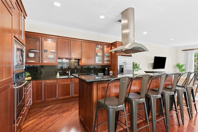 kitchen with island exhaust hood, dark wood-style floors, stainless steel appliances, a kitchen island, and tasteful backsplash