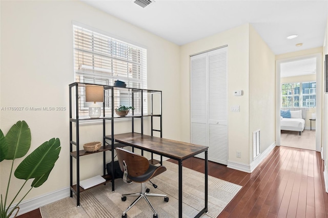 home office with wood finished floors, visible vents, and baseboards