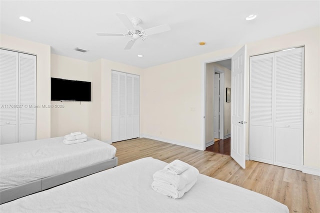 bedroom featuring light wood-type flooring, two closets, baseboards, visible vents, and recessed lighting