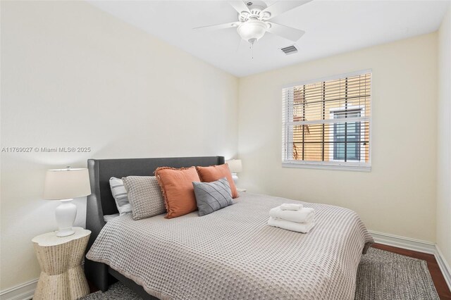 bedroom featuring baseboards, wood finished floors, visible vents, and a ceiling fan