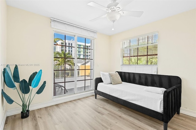 living area featuring baseboards, a ceiling fan, and wood finished floors