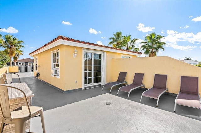 exterior space with a patio area, a tiled roof, fence, cooling unit, and stucco siding