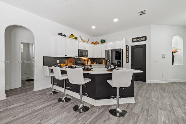 3007 W 8th St, Lehigh Acres, FL 33971 - kitchen featuring stainless steel refrigerator with ice dispenser, a peninsula, a breakfast bar area, light wood finished floors, and recessed lighting
