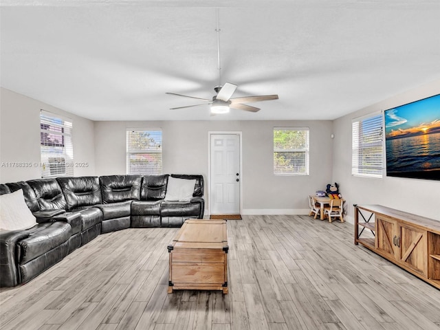 living area with light wood-style floors, baseboards, and ceiling fan