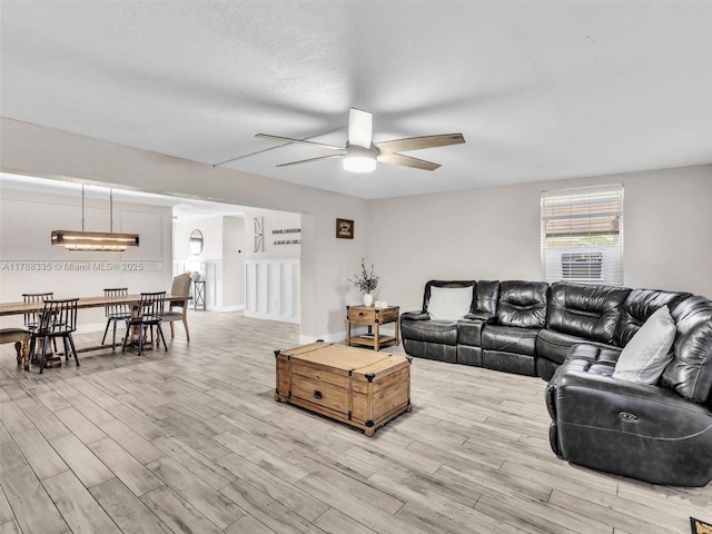 living room with wood finished floors, a ceiling fan, and baseboards