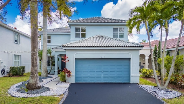 mediterranean / spanish-style house featuring a garage, a tile roof, stucco siding, and driveway