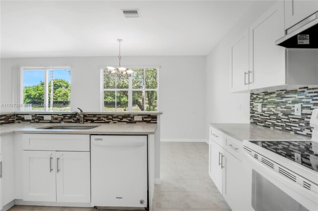 kitchen with under cabinet range hood, visible vents, a sink, white appliances, and a chandelier