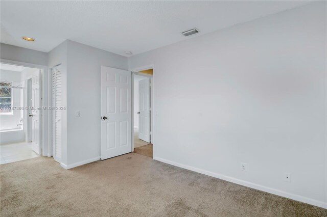 unfurnished bedroom featuring recessed lighting, ensuite bath, carpet, baseboards, and visible vents