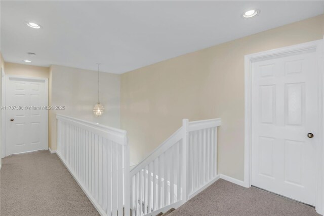 hallway with carpet flooring, recessed lighting, and an upstairs landing
