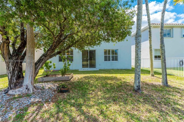 view of front of home with a front lawn, stucco siding, and fence