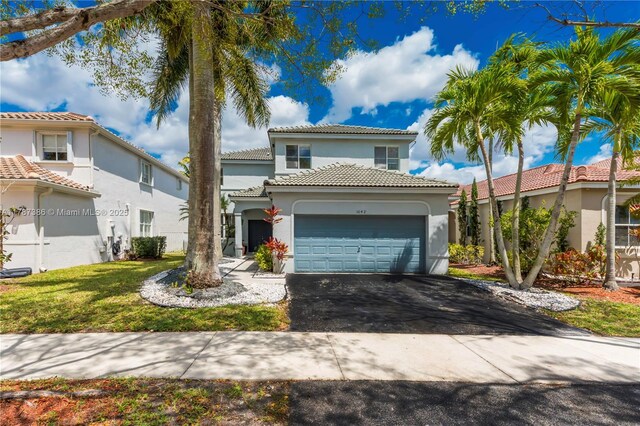traditional-style home with driveway, a tile roof, an attached garage, stucco siding, and a front lawn