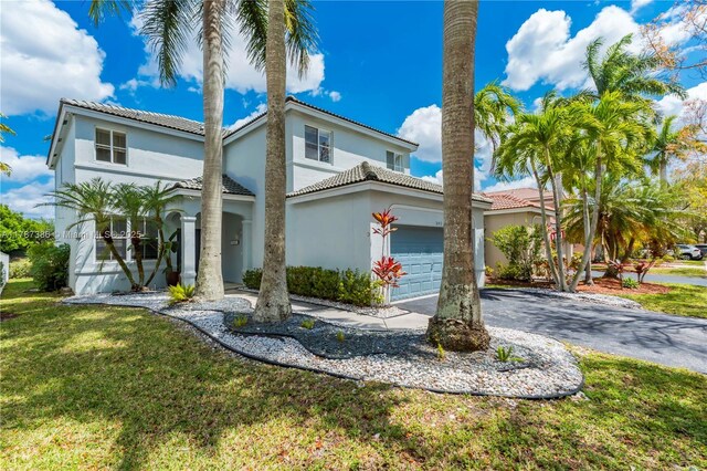 view of front of property featuring a tiled roof, a front lawn, aphalt driveway, an attached garage, and stucco siding