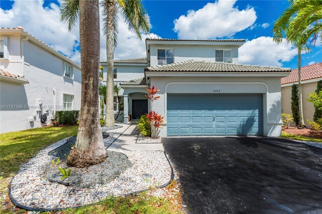 mediterranean / spanish-style house with stucco siding, aphalt driveway, a tile roof, and a garage