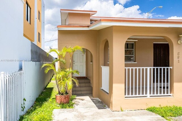 entrance to property with stucco siding and fence