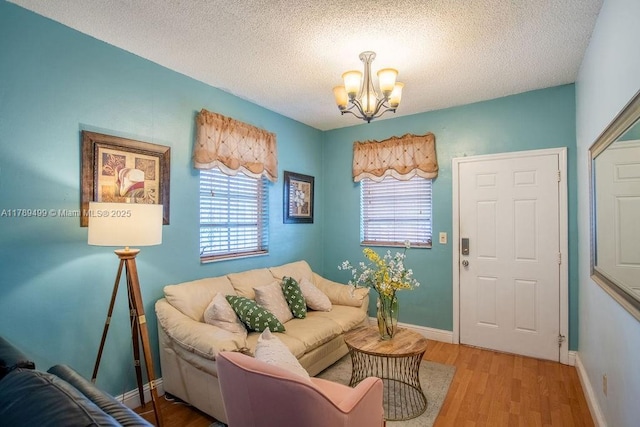 living room featuring an inviting chandelier, wood finished floors, a textured ceiling, and baseboards
