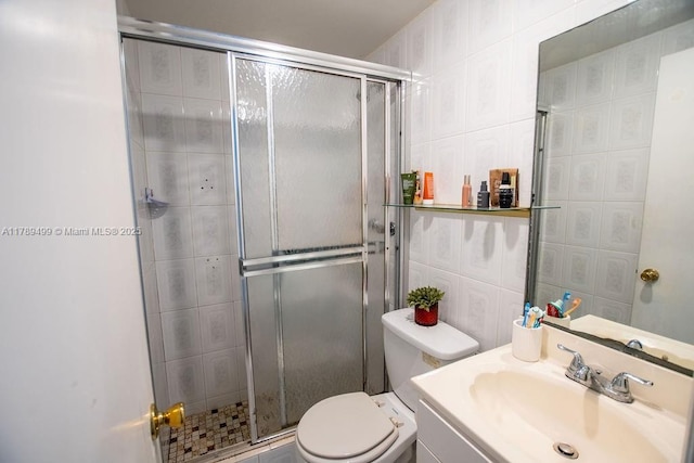 bathroom with vanity, toilet, a stall shower, and tile walls