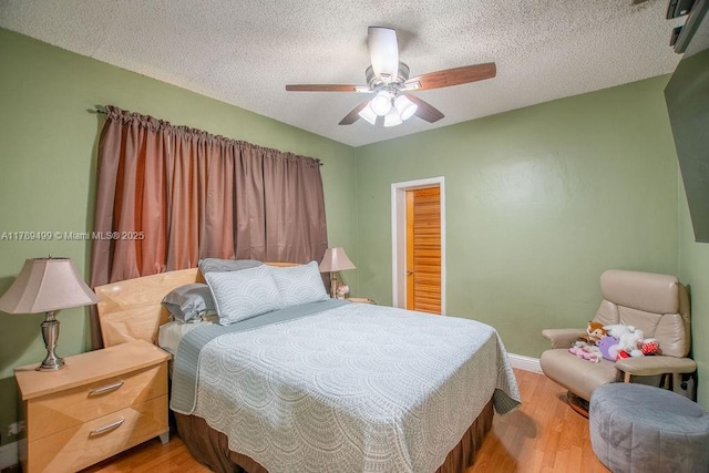 bedroom with light wood-style flooring, a textured ceiling, baseboards, and ceiling fan