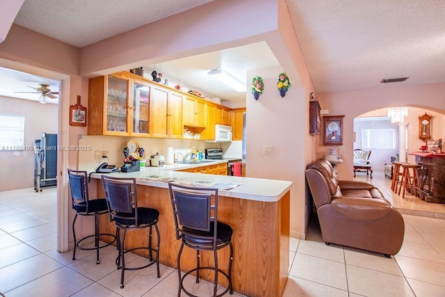 kitchen with arched walkways, a textured ceiling, visible vents, and stainless steel range with electric stovetop