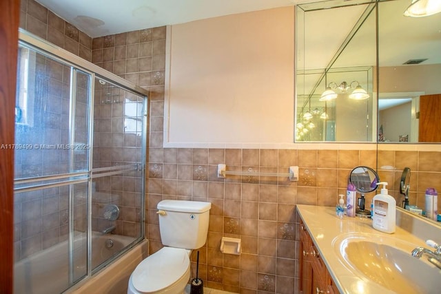 full bathroom with combined bath / shower with glass door, toilet, vanity, visible vents, and tile walls
