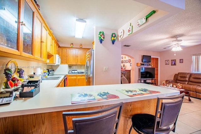 kitchen with open floor plan, light tile patterned flooring, light countertops, a peninsula, and appliances with stainless steel finishes