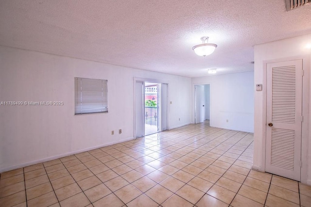empty room with a textured ceiling, visible vents, and light tile patterned floors