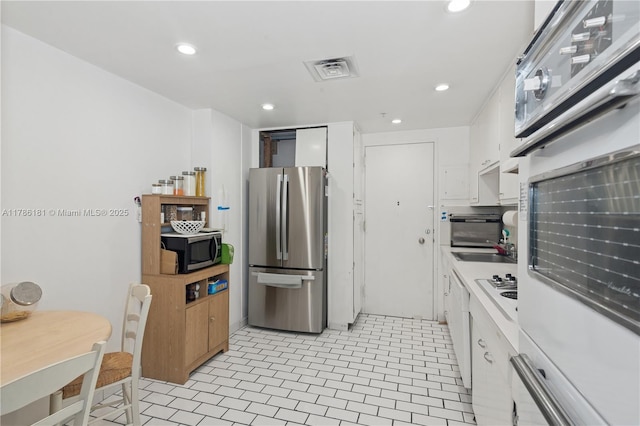 5055 Collins Ave Unit 5F, Miami Beach, FL 33140 - kitchen featuring stainless steel appliances, white cabinets, recessed lighting, and light tile patterned floors