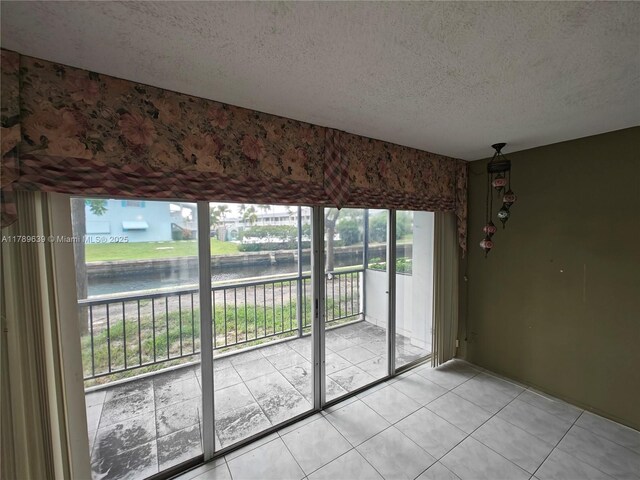 interior space with light tile patterned flooring, a textured ceiling, and a water view